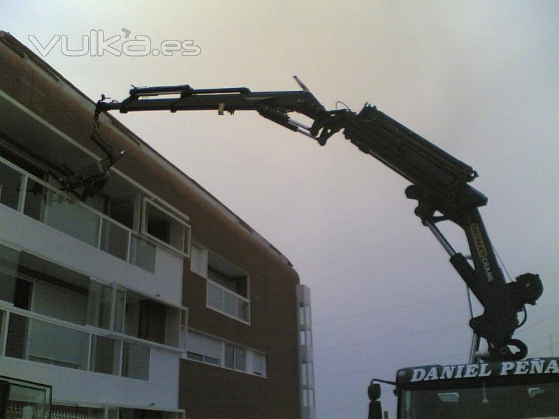 GRUA CON JIB METIENDO MATERIALES POR VENTANAS