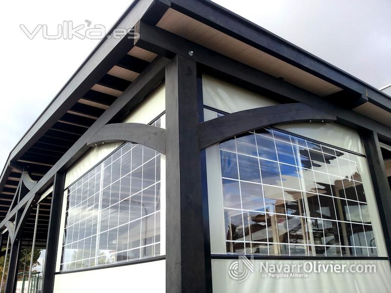 Detalle de pérgola de madera tratada para exteriores con cerramiento de lona con zona transparente. 