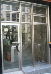 Puerta de comunidad en aluminio inox con travesanos reforzados y vidrio de seguridad laminar