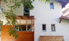 Aislamiento termico de eps,revocado de mortero en color blanco y detalles de madera en la fachada