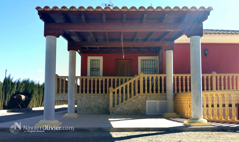 Pérgola adosada en madera sobre pilares de obra y cubierta de teja rústica. navarrolivier.com