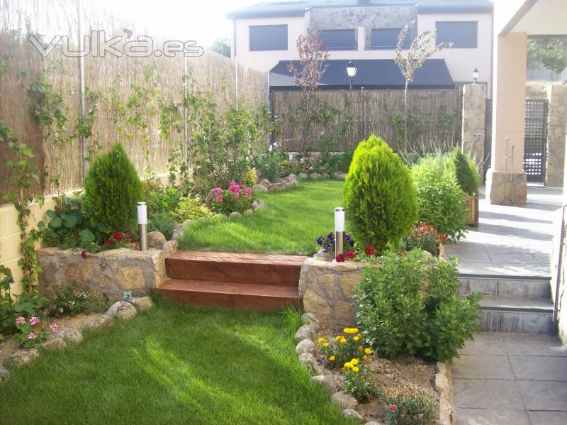 Diseño de jardín con césped antural y mezcla con jardineras de piedra y plantas.